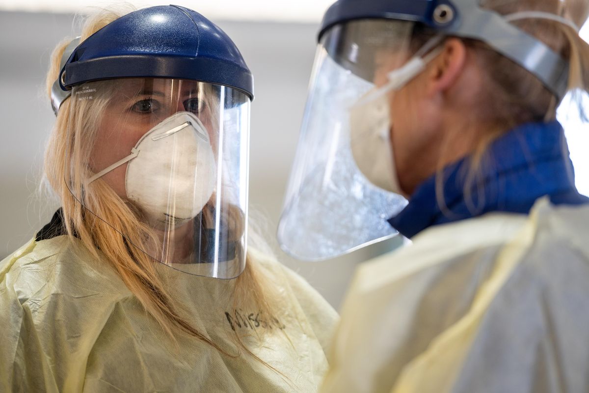 Missie Hunter, left, a nurse from MultiCare Deaconess Hospital, wears personal protective equipment as she assists people seeking a COVID-19 test in the indoor drive-up screening station at the Spokane Interstate Fair and Expo Center on April 2. (Colin Mulvany / The Spokesman-Review)