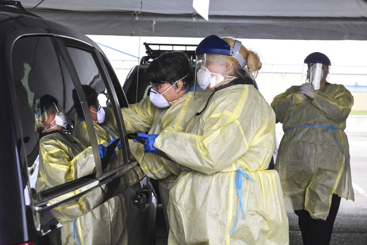 Medical workers attend to passengers in a vehicle entering the coronavirus screening center Wednesday, March 25, 2020, at the Spokane County Fair & Expo Center in Spokane. Local hospitals are not sharing where patients who test positive for the virus and require hospitalization are being treated, part of a nationwide balancing of privacy concerns with the public’s demand for information related to the pandemic. (Dan Pelle / The Spokesman-Review)