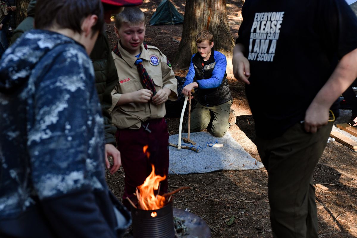 Dean Freudenberg, a Boy Scout with Troop 464 in the Spokane Valley, attempts to start a fire using a friction method with sticks as his fellow Scouts get a fire going using mosses and a ferro rod during the 2022 Fall Camporee at Cowles Scout Reservation on Oct. 29 near Newport, Wash.  (Tyler Tjomsland/The Spokesman-Review)