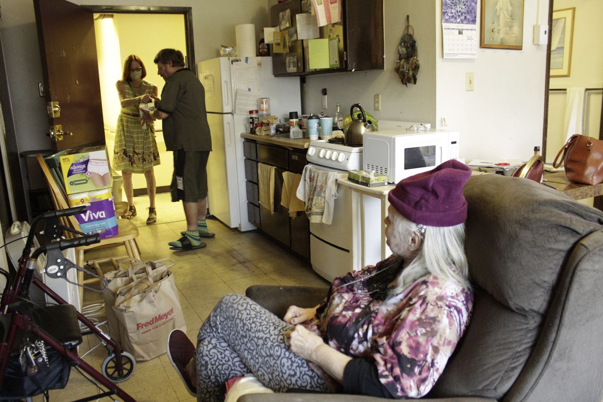 Joel Aslin accepts groceries for his neighbor, Karen Colby, from a volunteer with the nonprofit Store to Door on July 22, 2021, in Portland, Ore. Colby spent 10 days in the hospital with complications from heat stroke after nearly dying during a record-smashing heat wave that hit the Pacific Northwest earlier this summer with temperatures of up to 116 F. The unprecedented heat killed dozens of people in Oregon and hundreds across the region and was a wake-up call for the normally cool region as climate change accelerates.  (Gillian Flaccus)