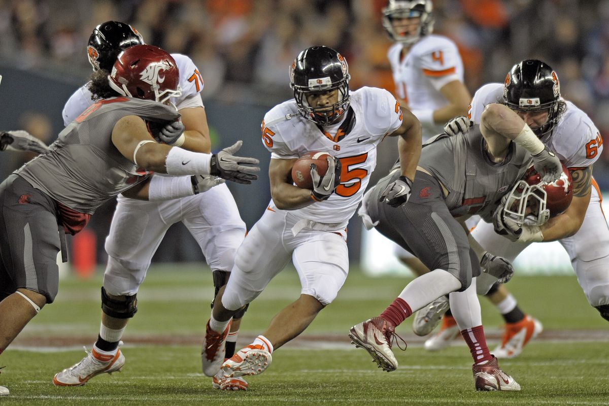 Oregon State running back Malcom Agnew (35) burst through the line as one WSU defender is pulled away by his pads and the other taken down by the facemask during first half action in their game in Seattle, Saturday, Oct. 22, 2011. (Christopher Anderson / Spokesman-Review)
