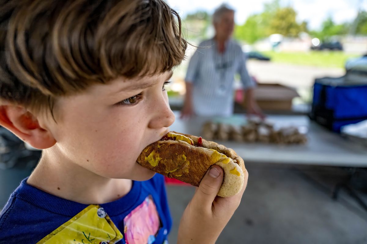 Kyrick Christianson, 8, eats his free hot dog lunch provided by Spokane Public Schools on Thursday at Liberty Park Aquatic Center. The Summer Meals Program is a federally funded child nutrition program created to help children up to the age of 18 receive the nourishment they need during summer break. (COLIN MULVANY/THE SPOKESMAN-REVIEW)