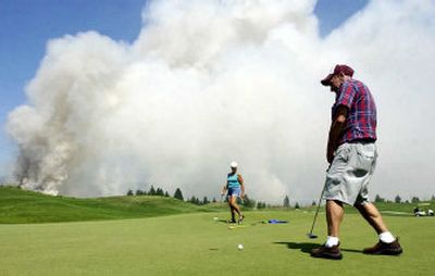 
Digger Thorman looks hopefully at a short putt on the back nine of Prairie Falls Golf Course on Tuesday as  smoke from burning grass fields is blown eastward. Thorman, who was golfing with his friend Fran Gordo, is a retired farmer from Bonners Ferry and he used to burn his hayfields. 
 (Jesse Tinsley / The Spokesman-Review)