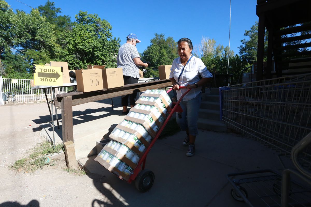 Barrios Unidos president Lupe Salazar pushes a dolly filled with canned food ahead of a food drive on Thursday, Sept. 23, 2021, in Chimayó, New Mexico.  (Cedar Attanasio)