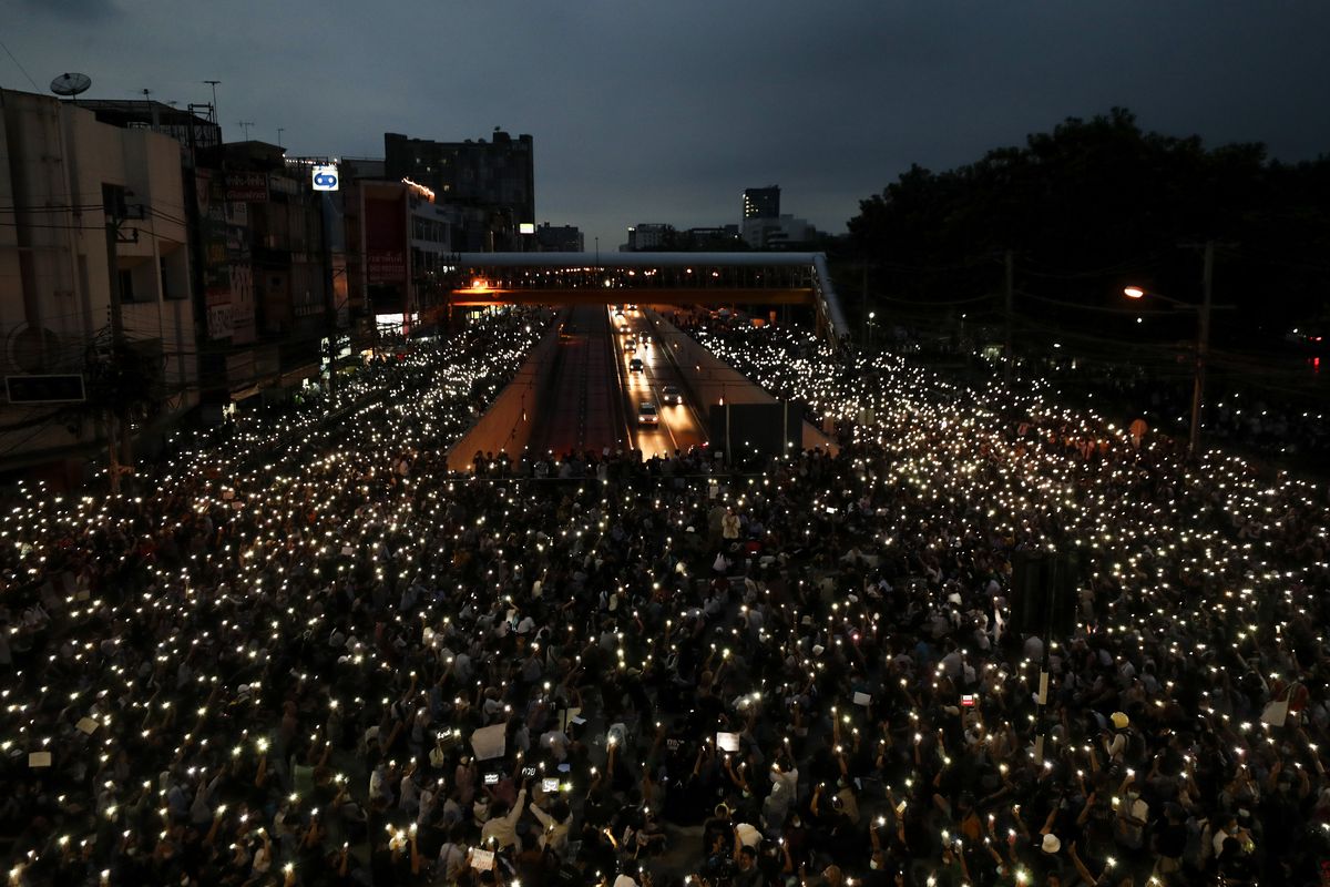 Pro-democracy activists wave mobile phones with lights during a demonstration at Kaset intersection, suburbs of Bangkok, Thailand, Monday, Oct. 19, 2020. Thai authorities worked Monday to stem a growing tide of protests calling for the prime minister to resign by threatening to censor news coverage, raiding a publishing house and attempting to block the Telegram messaging app used by demonstrators.  (Sakchai Lalit)