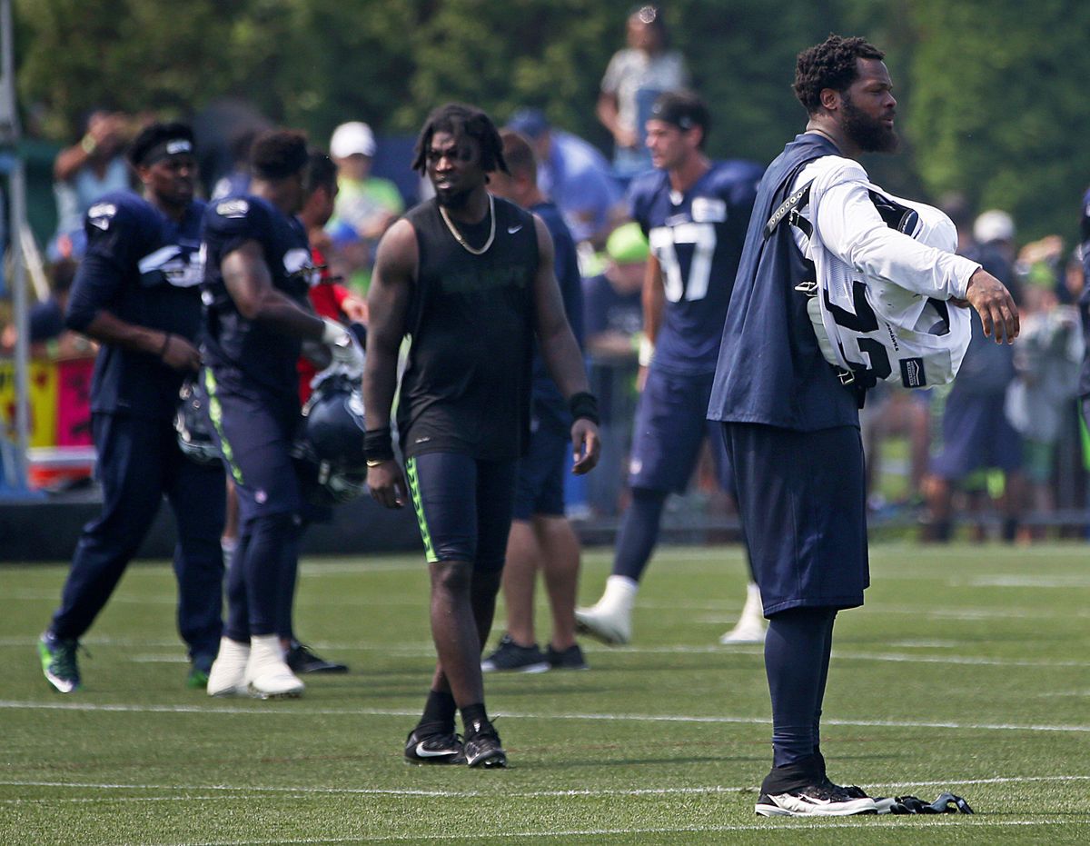 Seattle Seahawks defensive end Michael Bennett, right, takes off his pads after a practice which included fights, during NFL football training camp, Thursday, Aug. 3, 2017, in Renton, Wash. (Ken Lambert / Seattle Times via AP)