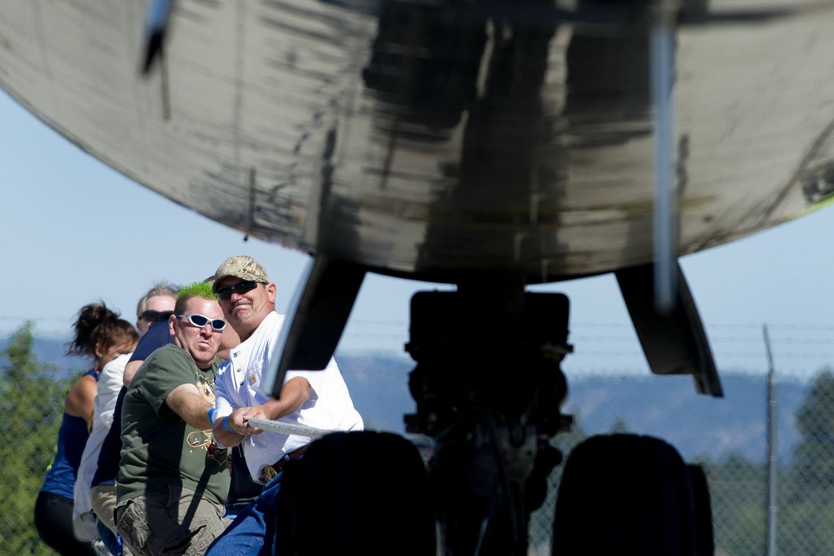 Bryan Pauley, left, and Rick Long grimace as they and the other members of GEG Terminal Velocity move a Boeing 727 during the Plane Pull on Saturday. The event – which organizers plan to hold each year – raised funds for Special Olympics. (Tyler Tjomsland)
