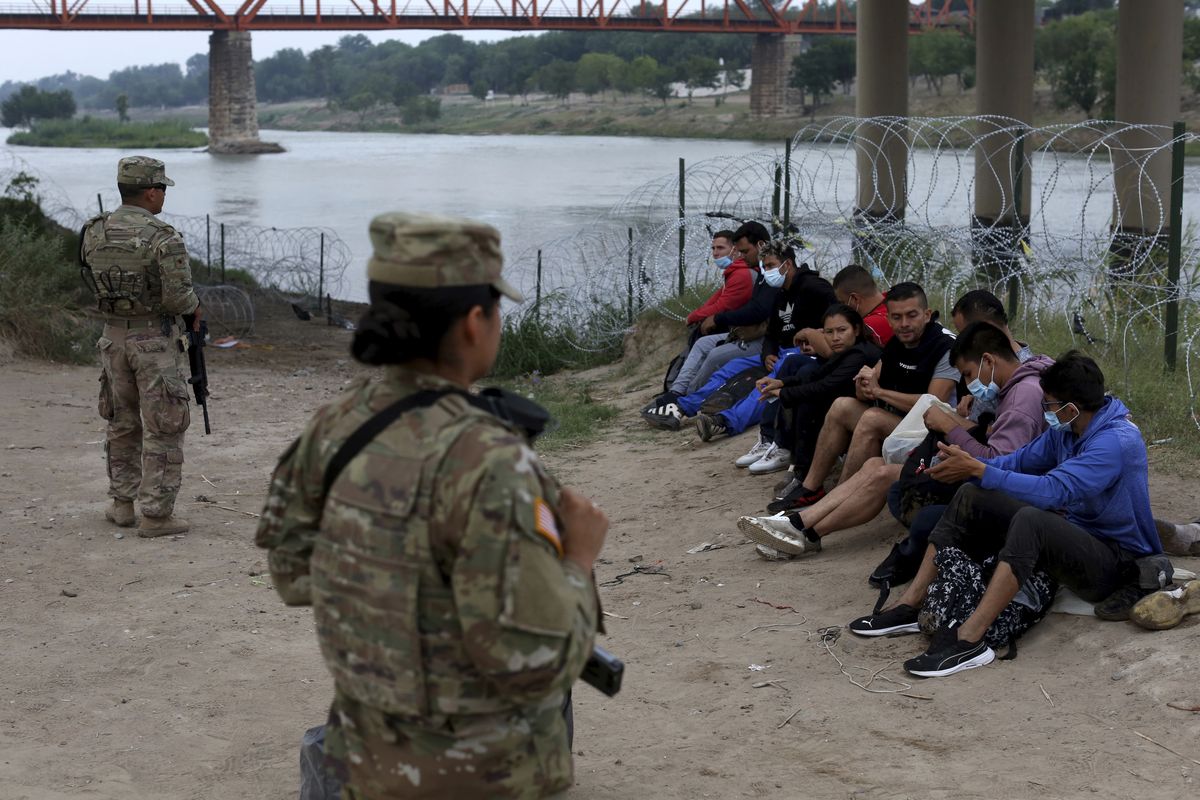 Migrants who had crossed the Rio Grande river into the U.S. are under custody of National Guard members Friday as they await the arrival of U.S. Border Patrol agents in Eagle Pass, Texas.  (Dario Lopez-Mills)