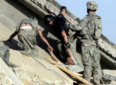 
A U.S. soldier and security contractor pull out a wounded Iraqi from the rubble of a bridge destroyed by an apparent suicide bomber on Sunday outside Mahmoudiya, about 20 miles south of Baghdad. Associated Press
 (Associated Press / The Spokesman-Review)