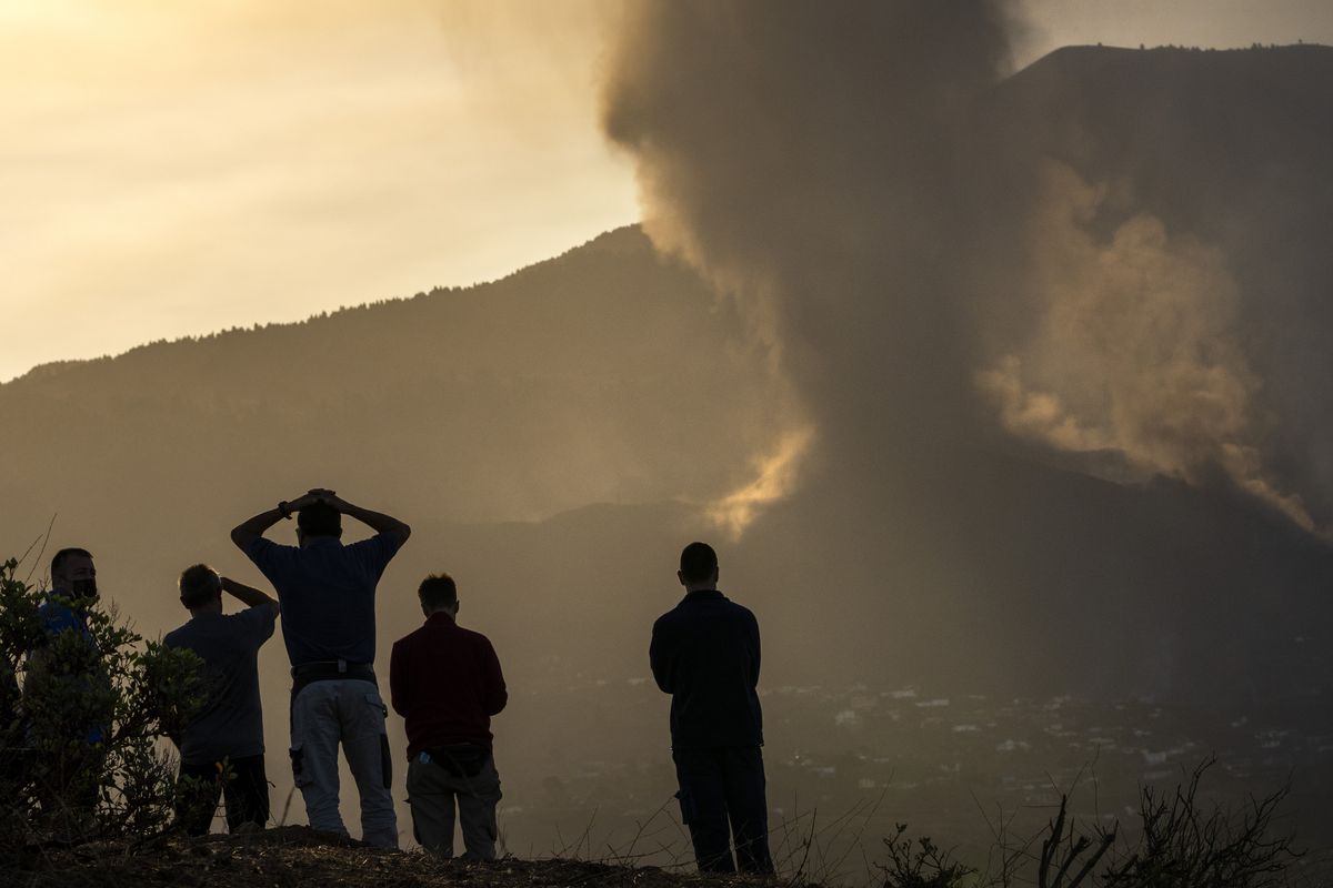 Residents look from a hill as lava continues to flow from an erupted volcano, on the island of La Palma in the Canaries, Spain, Friday, Sept. 24, 2021. A volcano in Spain’s Canary Islands continues to produce explosions and spew out lava, five days after it erupted. Two rivers of lava continue to slide slowly down the hillside of La Palma on Friday.  (Emilio Morenatti)