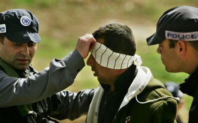 
Israeli police officers blindfold a detainee near Latrun, Israel, on Tuesday, following a dramatic high-speed chase of a van transporting a group of Palestinians allegedly carrying explosives. 
 (Associated Press / The Spokesman-Review)