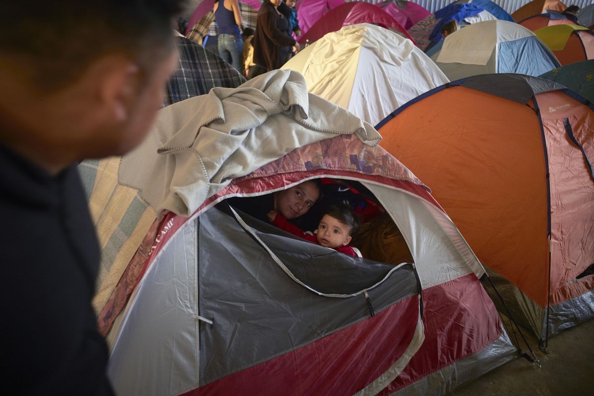 In this March 5, 2019, image, Ruth Aracely Monroy, center, looks out of the family’s tent alongside her 10-month-old son, Joshua, as her husband, Juan Carlos Perla, left, passes inside a shelter for migrants in Tijuana, Mexico. After fleeing violence in El Salvador and requesting asylum in the United States, the family was returned to Tijuana to await their hearing in San Diego. They were one of the first families to contend with a new policy that makes asylum seekers stay in Mexico while their cases wind through U.S. immigration courts. (Gregory Bull / Associated Press)