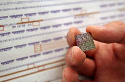 
Mario Paniccia, director of Intel Corp.'s photonics lab, holds up a 16 millimeter by 16 millimeter chip that contains eight silicon laser chips with a backdrop of a test chip layout in his lab in Santa Clara, Calif.
 (Associated Press / The Spokesman-Review)