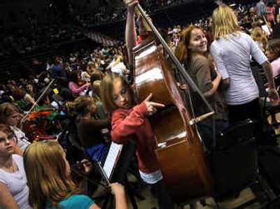 
String bass player Olivia Payne and her friend Madeline Antcliff, right, of Jefferson Elementary School, squeeze their way through the throngs of instruments just before the opening song at the annual Band and Strings Spectacular Concert on Tuesday at Spokane Arena. 
 (The Spokesman-Review)