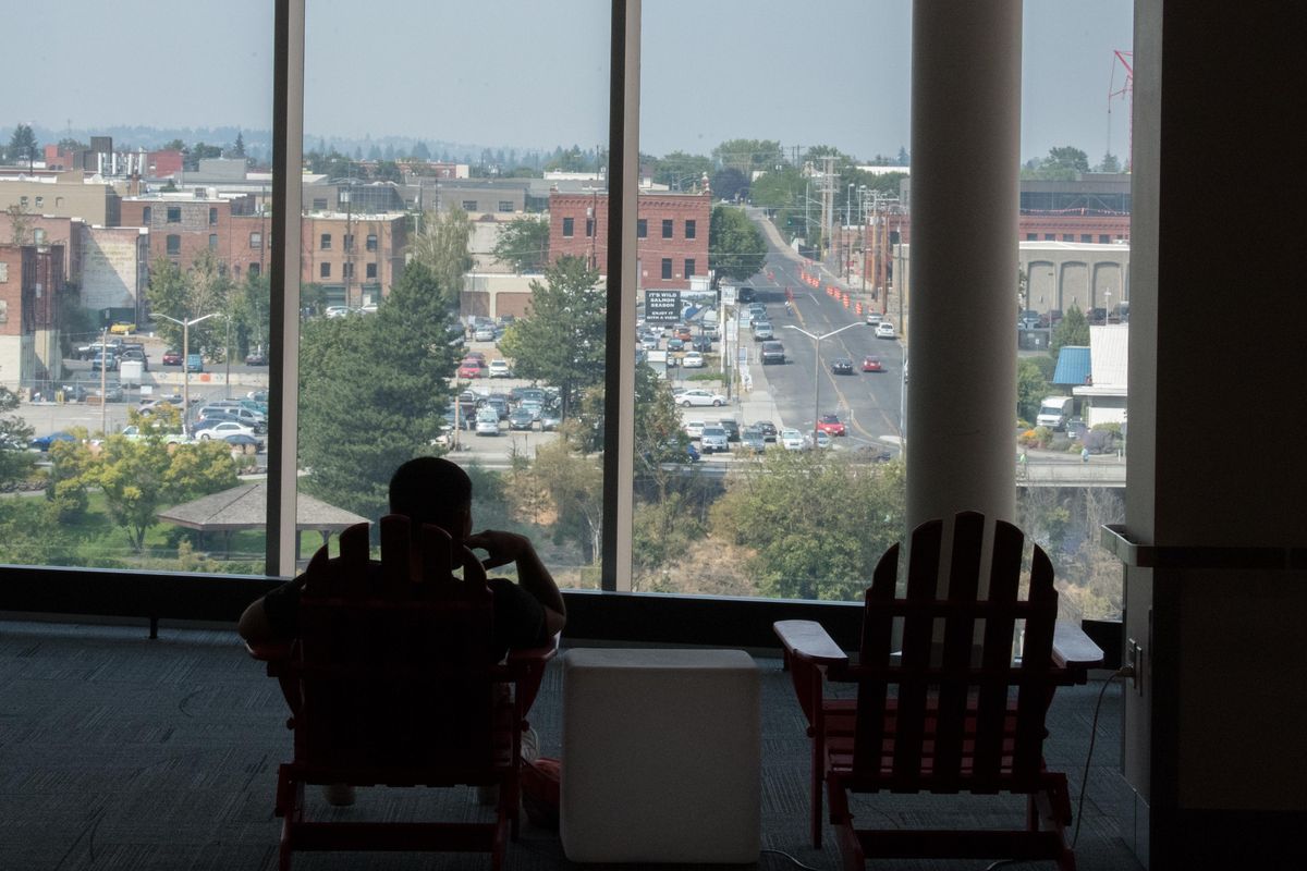 Tress Big Day, 33, surveys the sweltering North Spokane skyline as he relaxes in the air conditioned downtown Spokane Public Library on Thursday, Aug. 9, 2018, in Spokane, Wash. (Tyler Tjomsland / The Spokesman-Review)