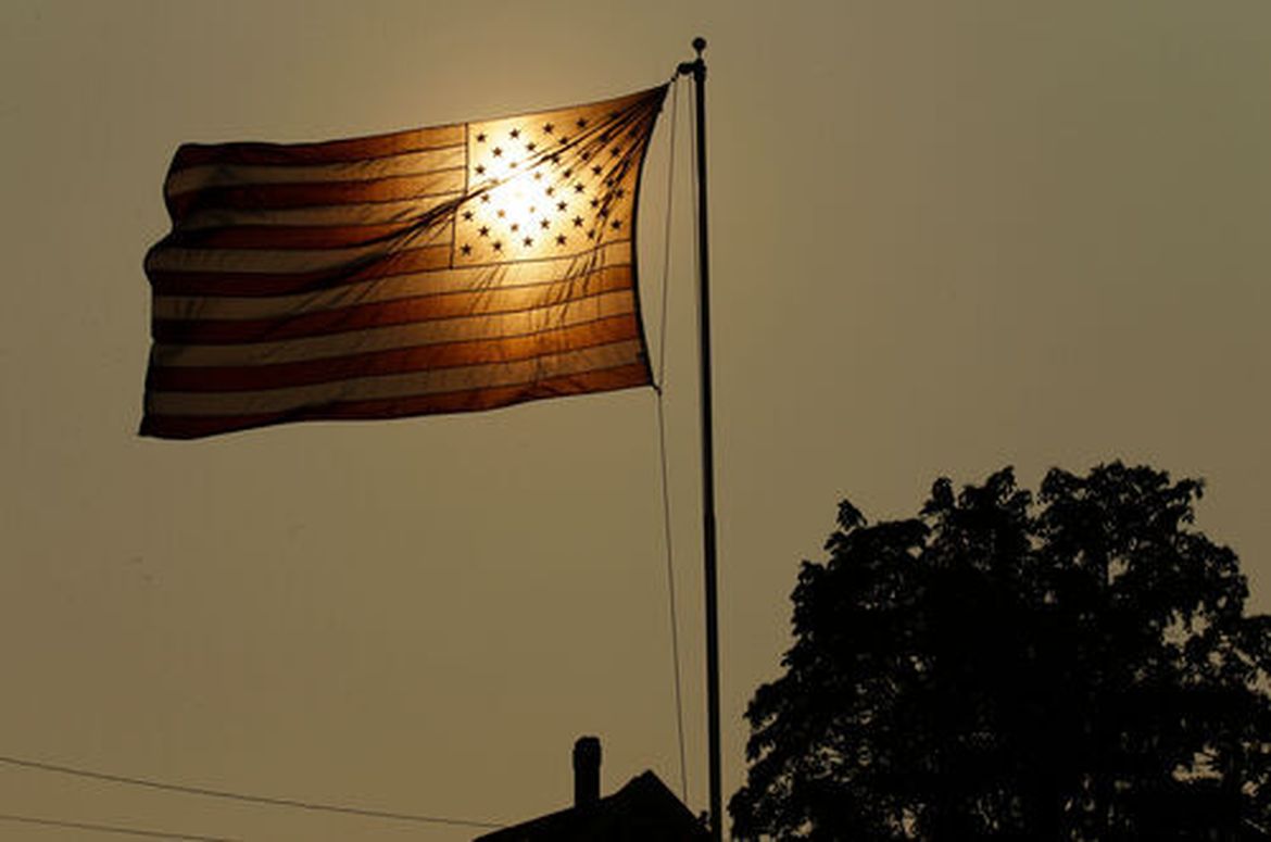 The sun shines through a U.S. flag flying in the wind in Tacoma.