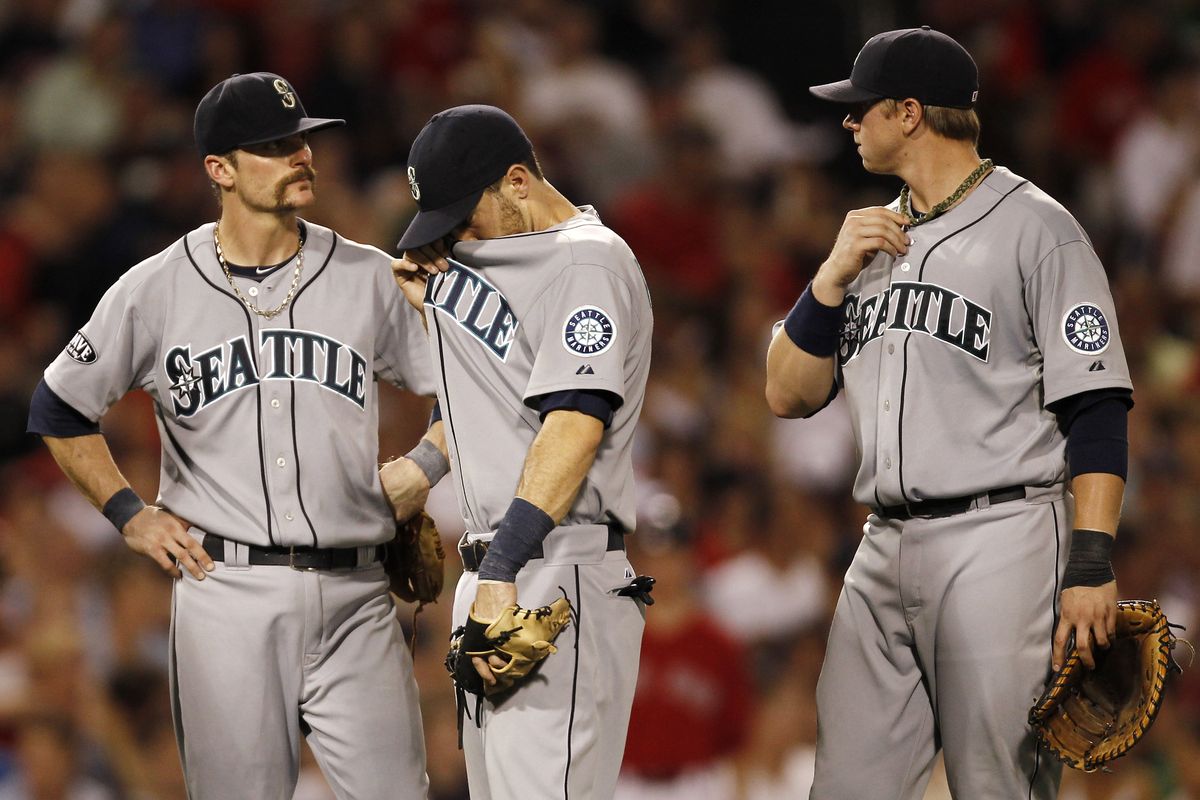 M’s infielders Brendan Ryan, left, Dustin Ackley, center, and Justin Smoak wait for a pitching change during Boston’s five-run seventh. (Associated Press)