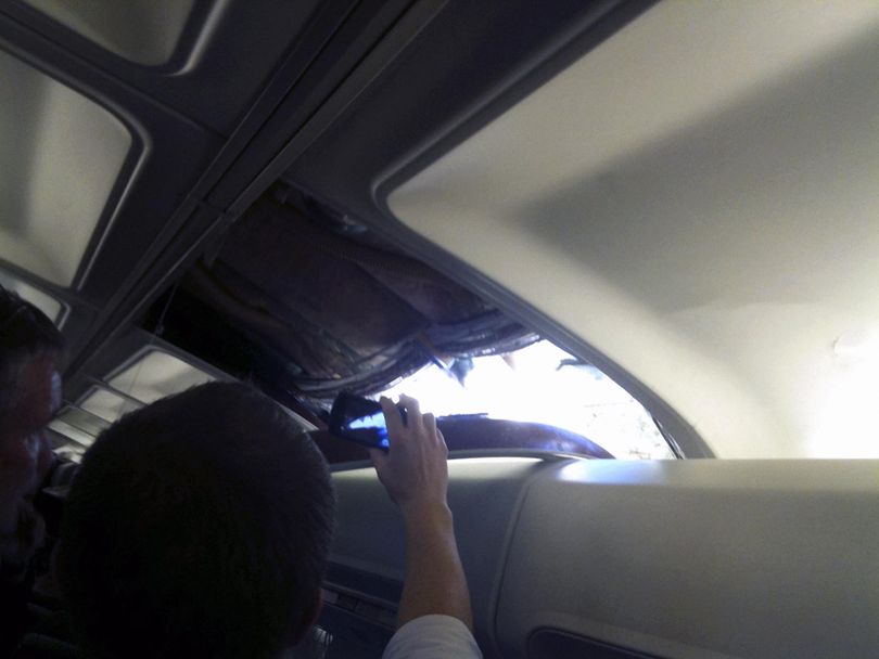 In this photo by passenger Brenda Reese, passengers take photos with cellphones of an apparent hole in a Southwest Airlines aircraft Friday in Yuma, Ariz. (Associated Press)