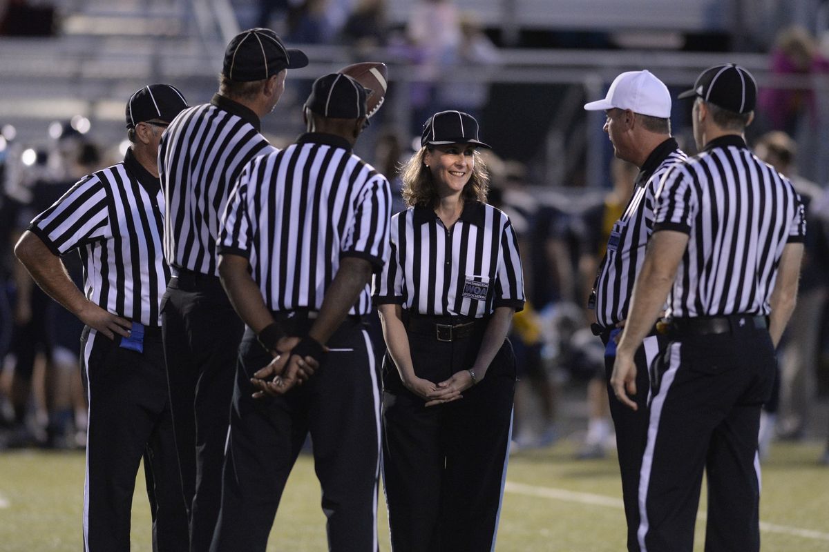 Mary Harvill stands with the rest of the referees and waits for the national anthem to begin before a football game Sept. 26 at Gonzaga Prep. It was her first game as a high school varsity referee. She worked the “box,” carrying the marker and working with the chain crew. (Jesse Tinsley)