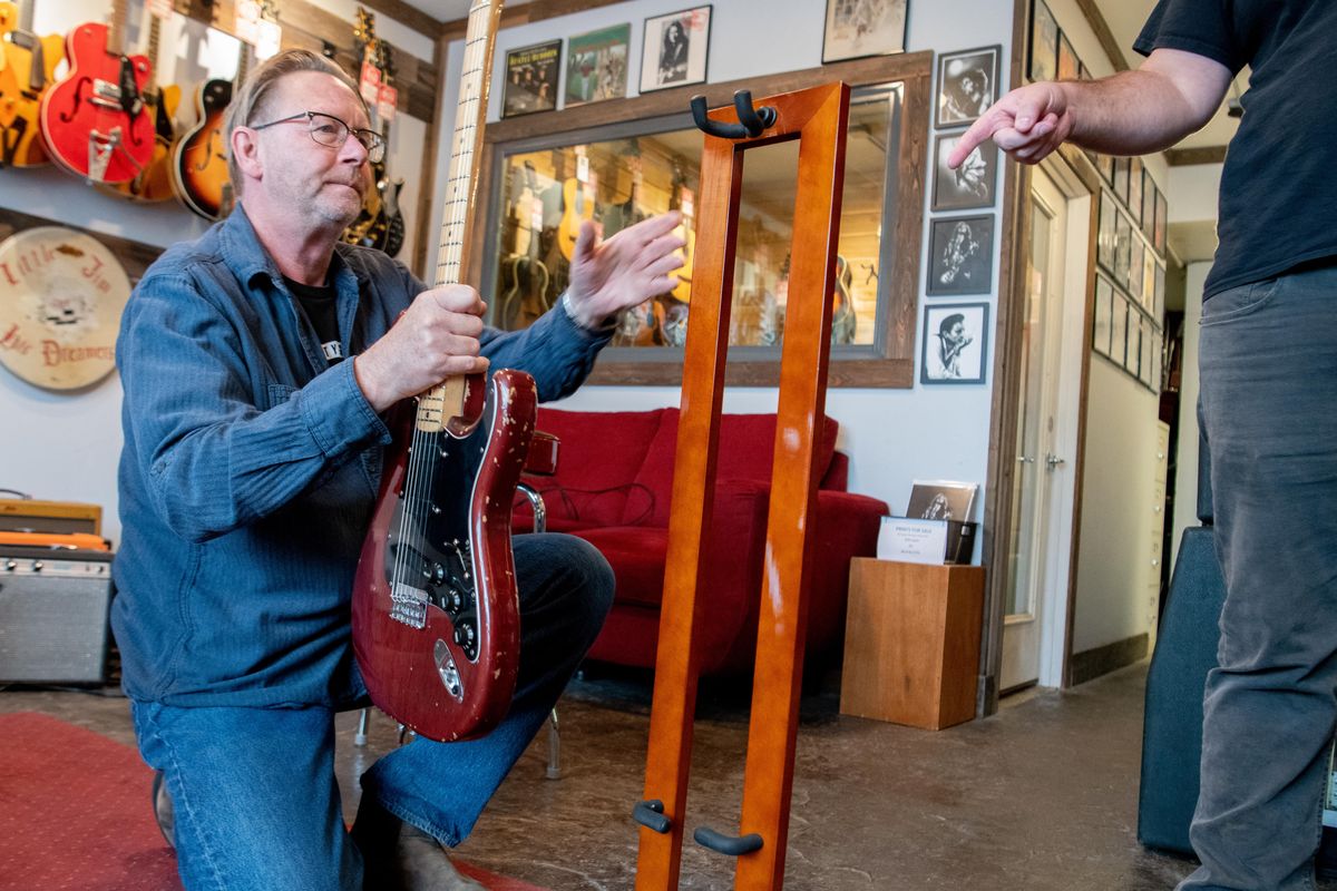 Tom Ramsey of River City Guitars in Spokane puts a 1979 Fender Stratocaster guitar that belonged to Jimmy Page of Led Zeppelin fame onto a display stand Wednesday. (Jesse Tinsley / The Spokesman-Review)