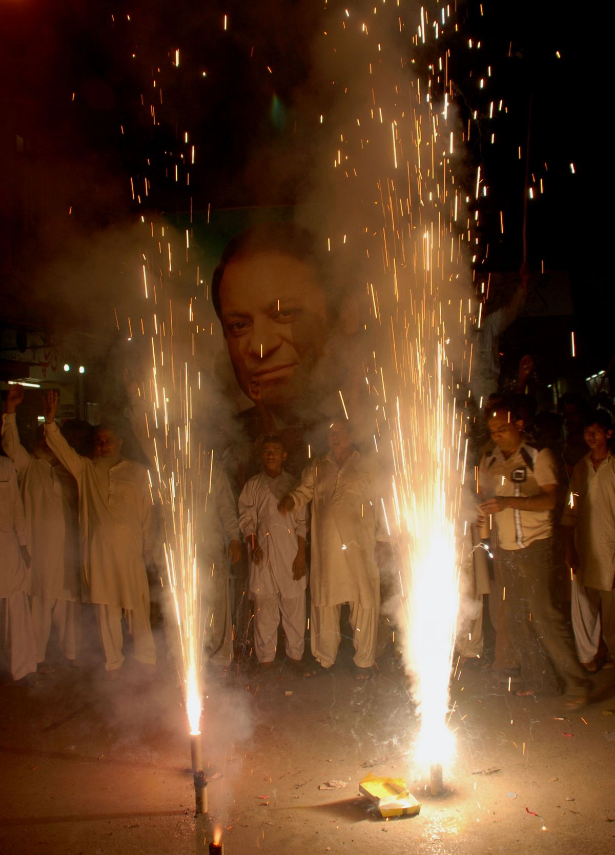 Against the backdrop of a poster of former Prime Minister Nawaz Sharif, Pakistanis in Multan celebrate the resignation of President Pervez Musharraf with dancing and fireworks.  (Associated Press / The Spokesman-Review)