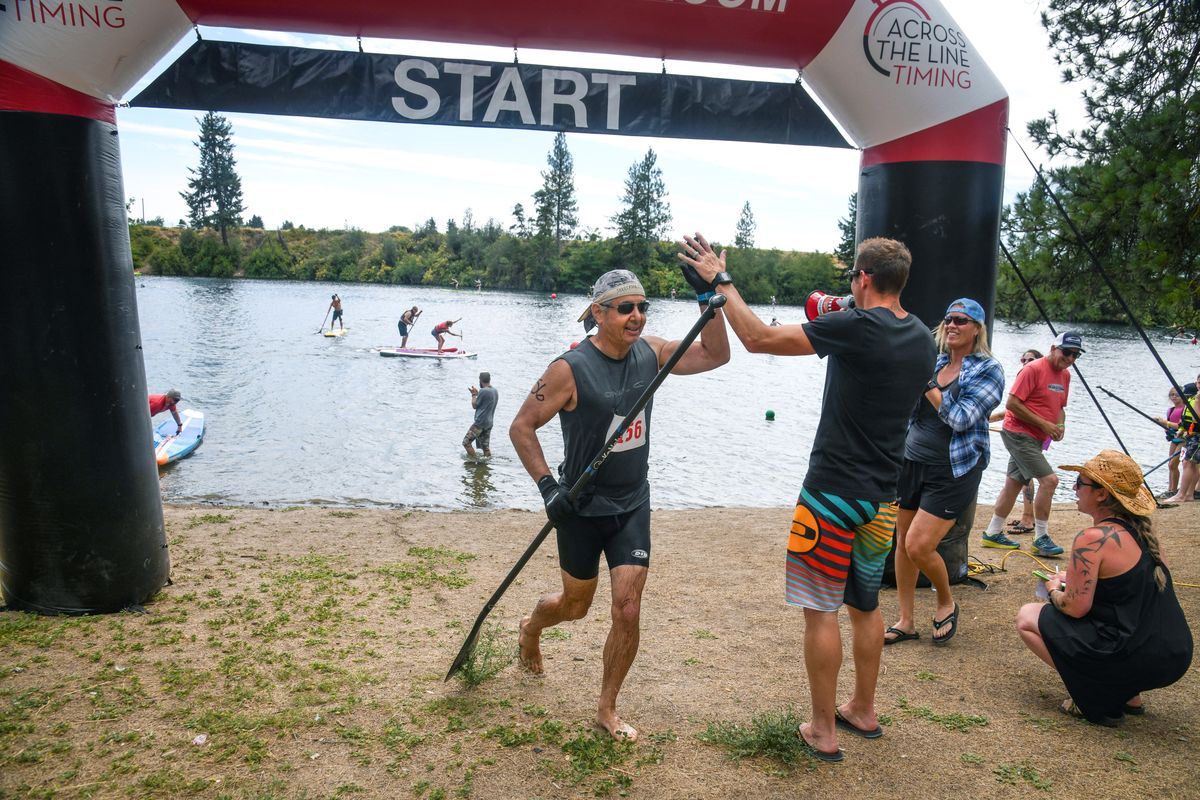 Travis Prewitt, 67, of Liberty Lake, being congratulated by at the finish line by Tony Parks. wins the Spokatopia SUP Cup recreation division on Sunday at Boulder Beach. (Dan Pelle / The Spokesman-Review)