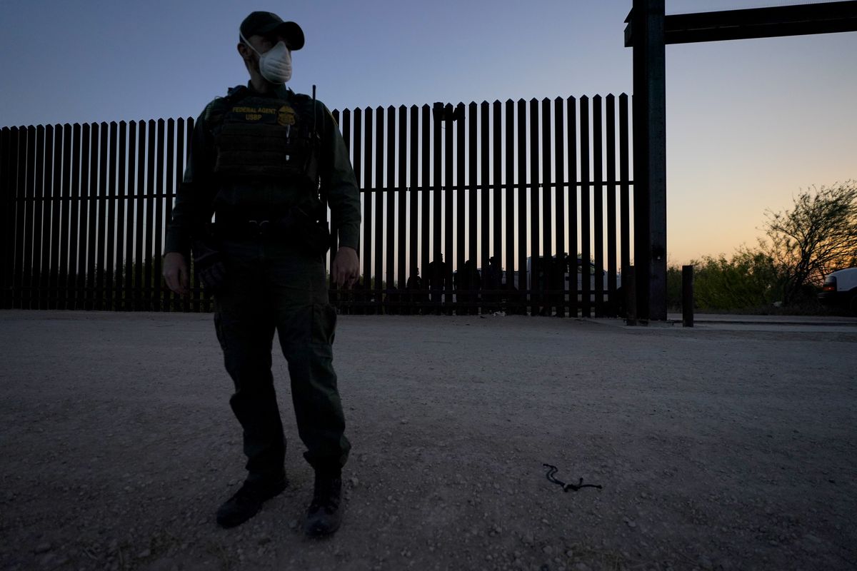 A U.S. Customs and Border Protection agent looks on near a gate on the U.S.-Mexico border wall as agents take migrants into custody, Sunday, March 21, 2021, in Abram-Perezville, Texas. The fate of thousands of migrant families who have recently arrived at the Mexico border is being decided by a mysterious new system under President Joe Biden. U.S. authorities are releasing migrants with “acute vulnerabilities” and allowing them to pursue asylum. But it’s not clear why some are considered vulnerable and not others. (Julio Cortez)