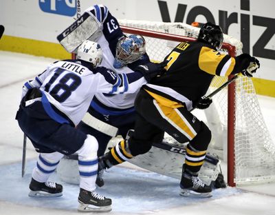 Pittsburgh Penguins' Matt Cullen (7) gets the puck past Winnipeg Jets goaltender Connor Hellebuyck (37) for a goal with Bryan Little (18) defending during Friday’s game. Pittsburgh won 4-0. (Gene J. Puskar / Associated Press)