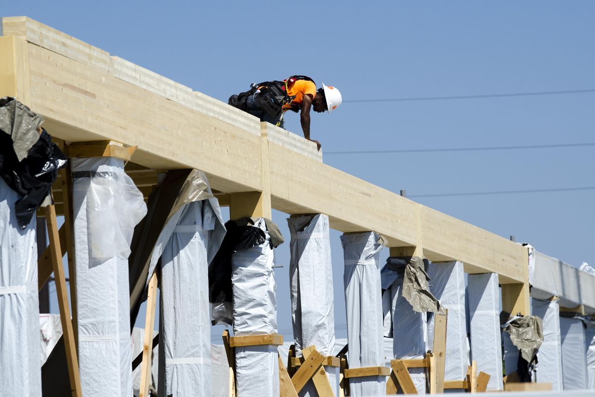 A workers sits atop the Catalyst Building at the south landing of the University District Gateway Bridge in July. The net-zero building, constructed with beams of super-strong cross-laminated timber, is on track to be complete in 2020. (Jesse Tinsley / The Spokesman-Review)