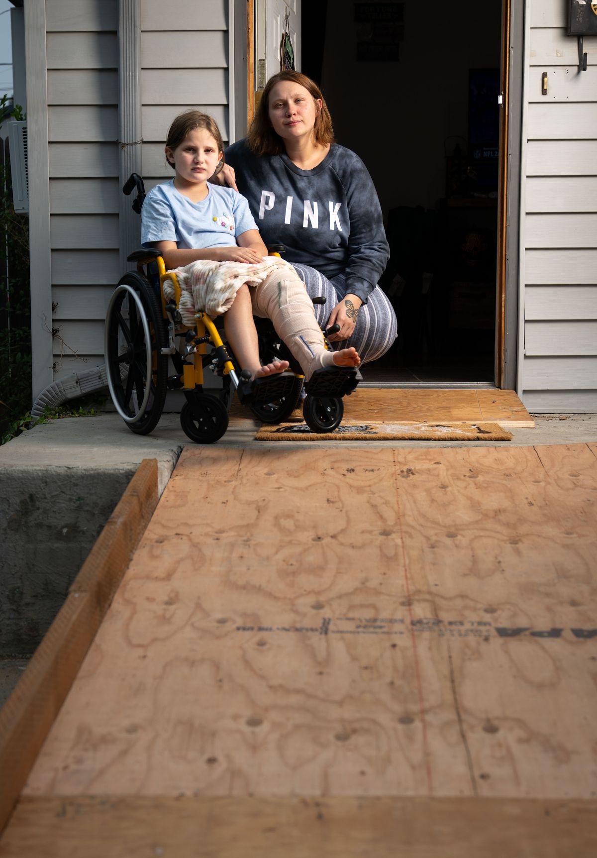 Nine-year old Mayzee Wilson and her mom, Bethany Freeland, pose for a photo at the top of a newly installed wheelchair ramp at their northside home Monday. Mayzee and Freeland’s boyfriend, Billy Cochran, were hit and injured by a truck while riding a motorcycle home. They are worried about money as Cochran is still in the hospital recovering.  (COLIN MULVANY)