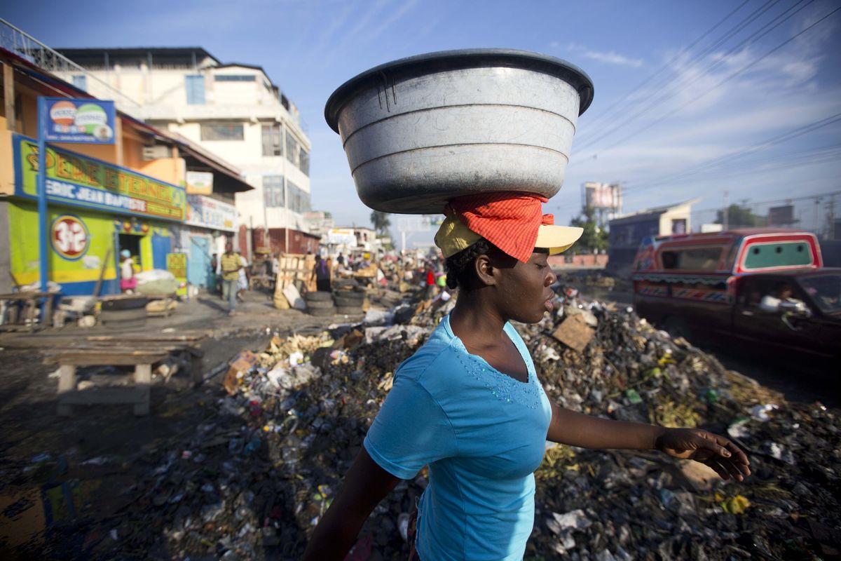 In this Saturday, May 21, 2016, photo, a vendor walks past trash near a street market in Port-au-Prince, Haiti. Some experts worry a relatively large number of microcephaly cases could hit Haiti later this year when women infected with Zika in early 2016 start giving birth. (Dieu Nalio Chery / Associated Press)