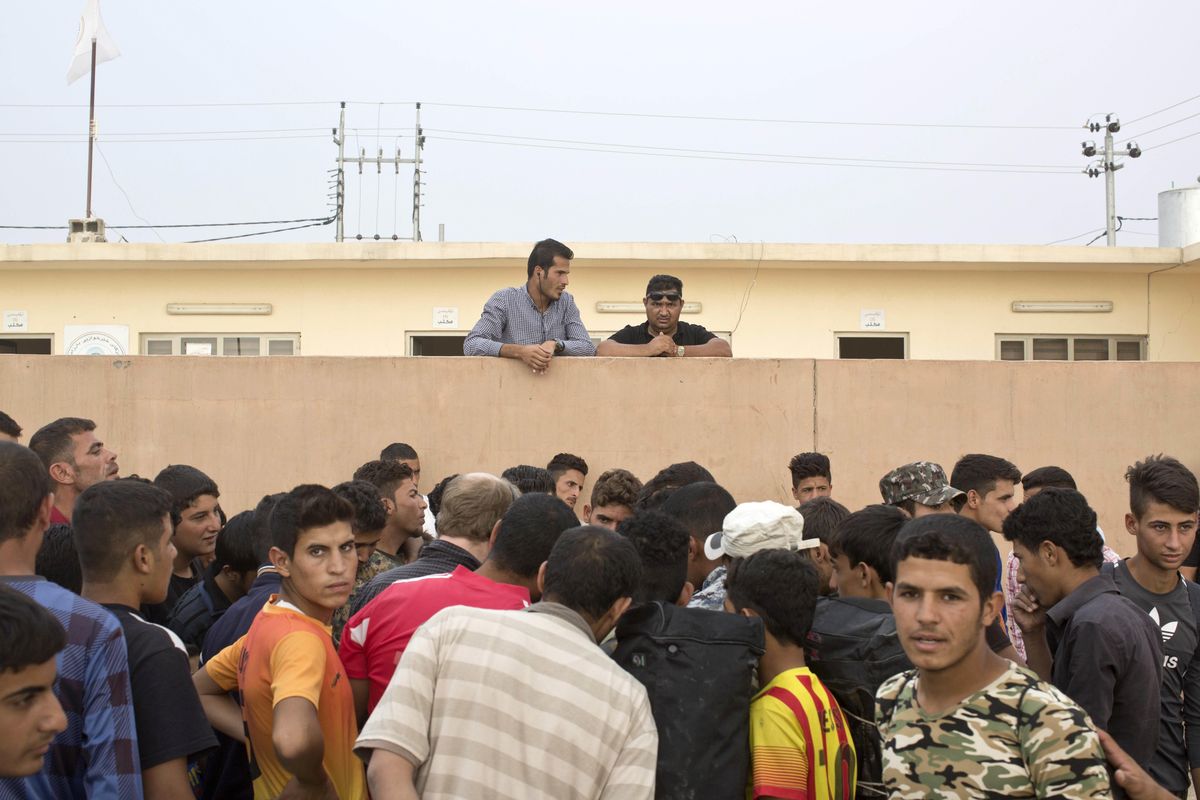 People gather as aid is being distributed at a camp for displaced families in Dibaga, near Mosul, Iraq, Monday, Oct. 24, 2016. (Marko Drobnjakovic / AP)