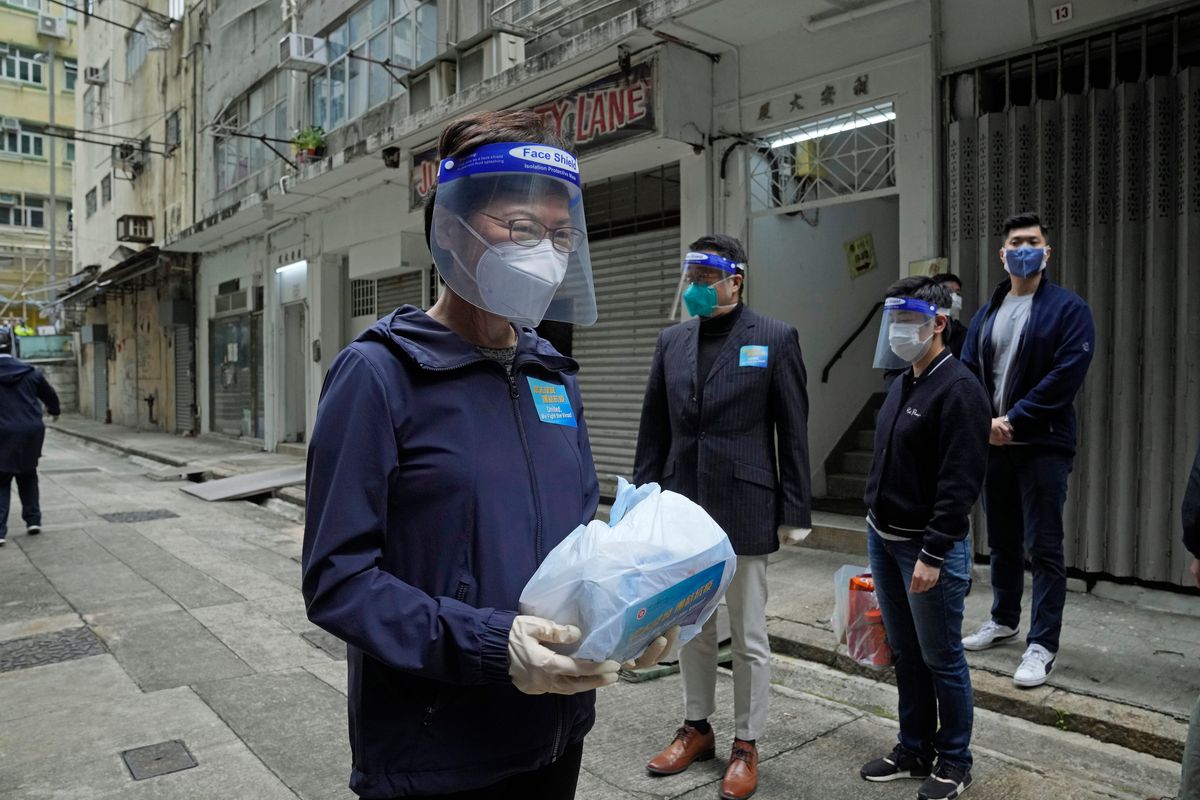 Hong Kong Chief Executive Carrie Lam, left, holds a package of coronavirus prevention materials to be delivered to people on Saturday during an anti-epidemic event in Hong Kong.  (Kin Cheung)
