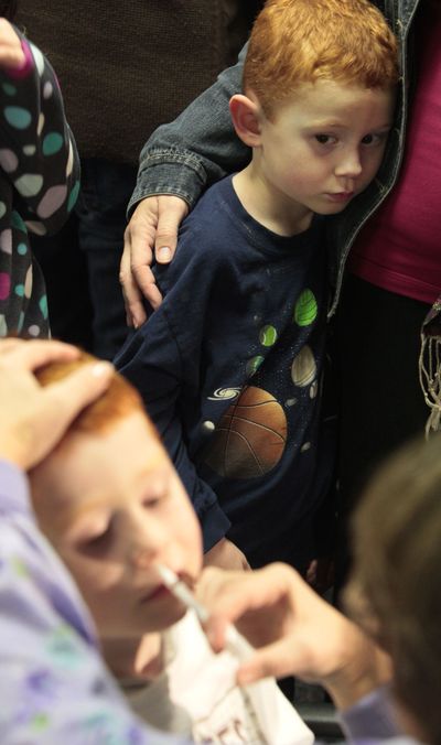 Matthew Vanderwater, 4, of Naperville, Ill., is held by his mother, Jodi, as he watches his brother Mark get the H1N1 nasal spray vaccine Thursday  in Wheaton, Ill.  (Associated Press / The Spokesman-Review)