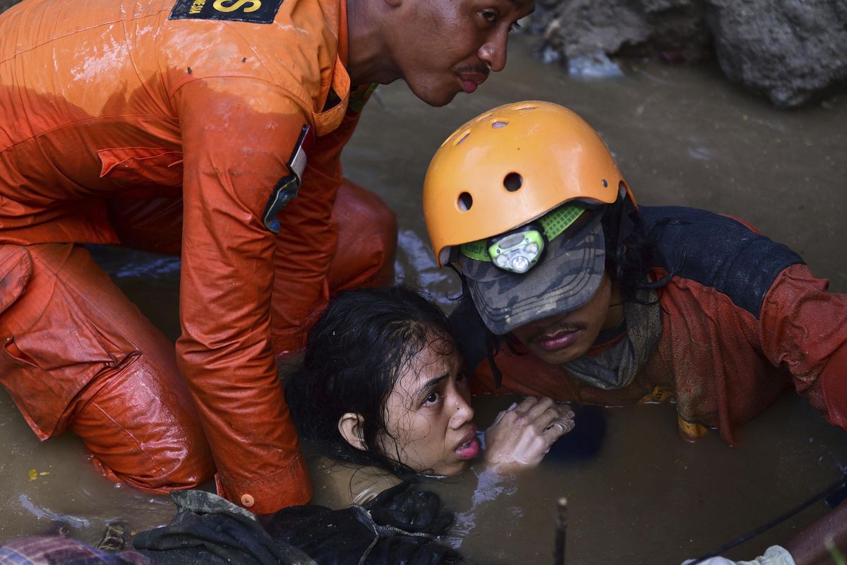 Rescuers evacuate an earthquake survivor by a damaged house following earthquakes and tsunami in Palu, Central Sulawesi, Indonesia, Sunday, Sept. 30, 2018. (Arimacs Wilander / Associated Press)