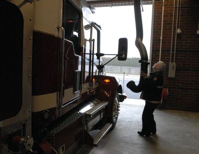 Spokane Valley Fire Department Station 9 truck driver Dan Wittenberg attaches the exhaust hose of the Nederman System to the fire truck after it was backed into the new station Thursday. (J. BART RAYNIAK / The Spokesman-Review)