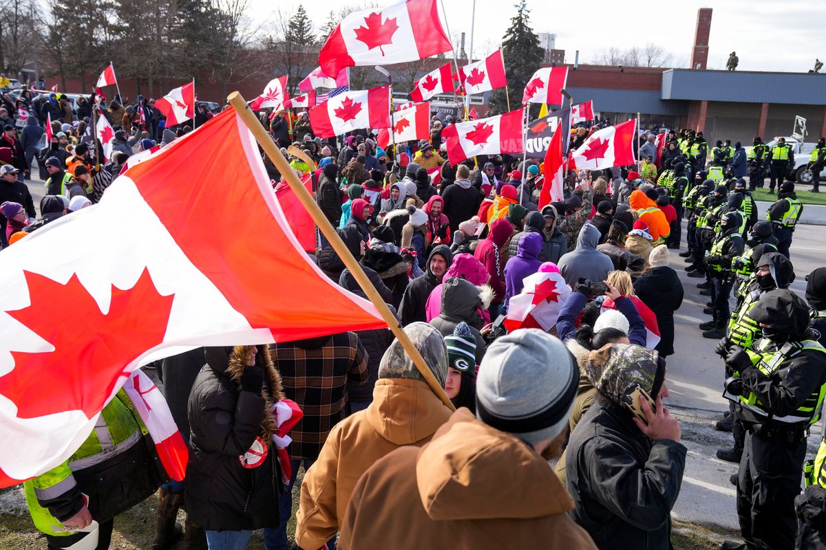 Police officers hold a line as protesters against COVID-19 restrictions march in Windsor, Ont., Saturday, Feb. 12, 2022. The demonstrations at the Ambassador Bridge, downtown Ottawa and elsewhere have targeted vaccine mandates and other coronavirus restrictions and vented fury toward Prime Minister Justin Trudeau, who has called the protesters a “fringe” of Canadian society. (Nathan Denette)