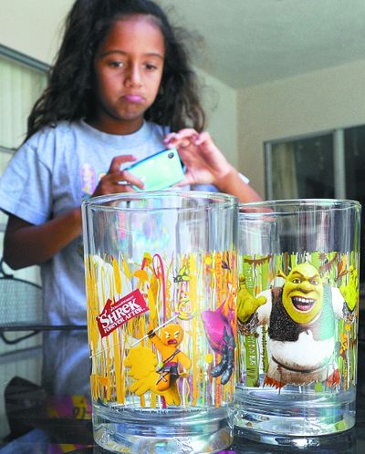 Jasmine Matta, 7, takes a photo of her “Shrek”-themed glasses, distributed in McDonald's Happy Meals, in West Hollywood, Calif. (Associated Press)