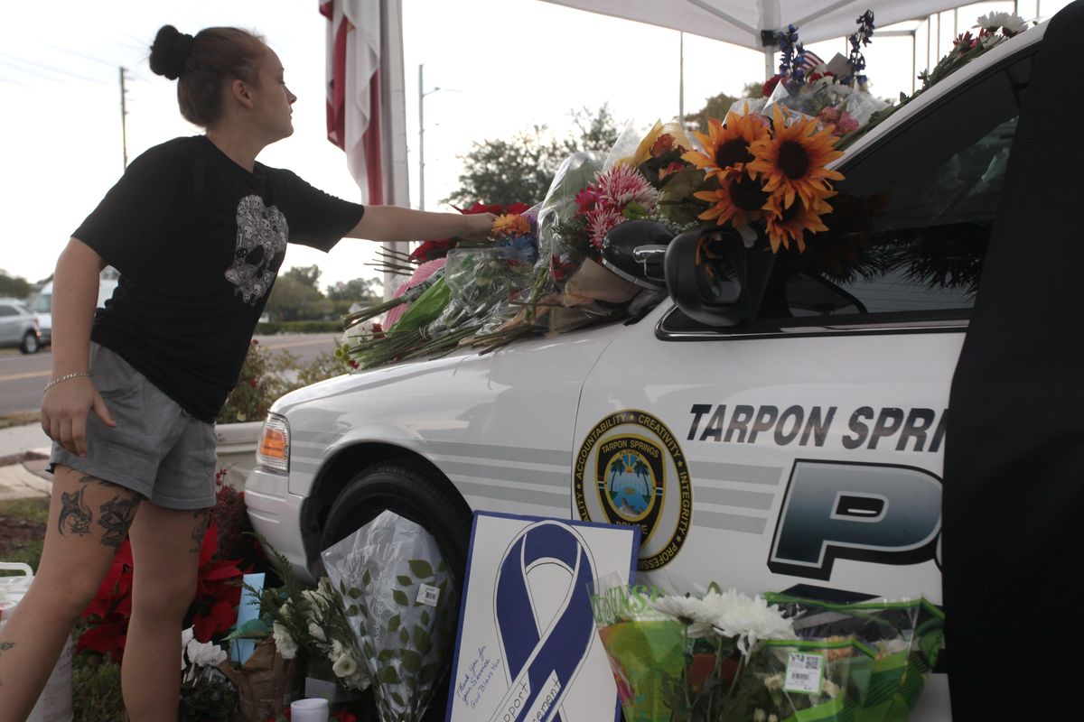 A woman leaves flowers Sunday at a memorial for slain police Officer Charles Kondek in Tarpon Springs, Fla. (Associated Press)