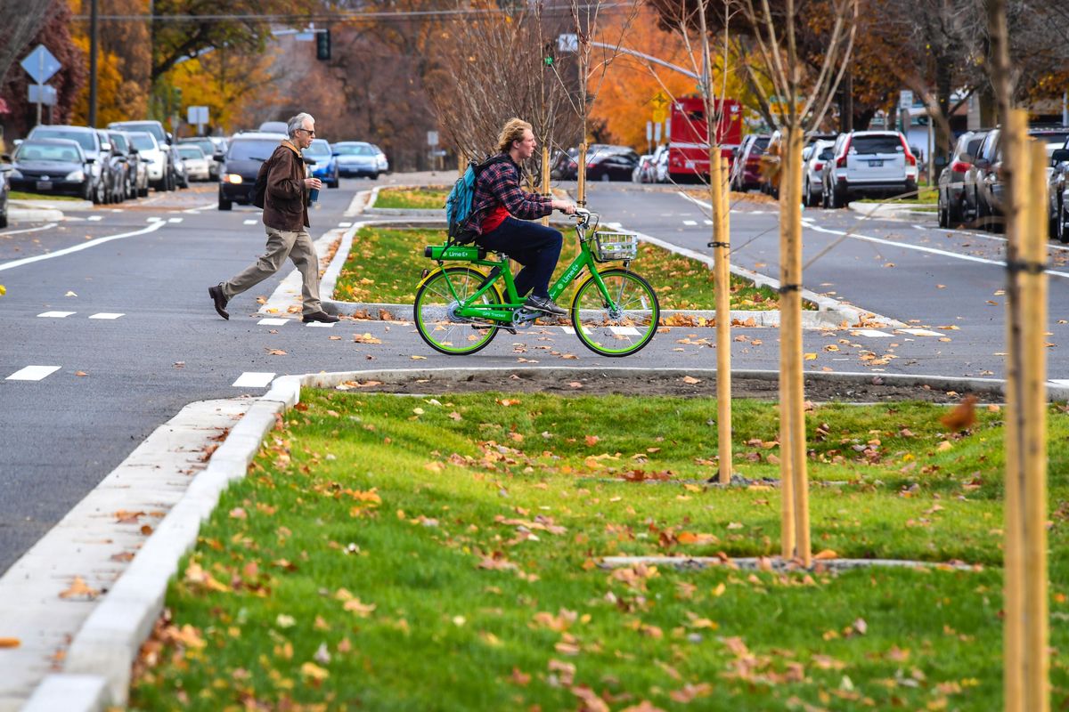 A pedestrian and a cyclist cross Sharp Avenue at Standard Street on Nov. 2 near the Gonzaga University campus. Sharp now has permeable pavement and bike lanes. (DAN PELLE/The Spokesman-Review)
