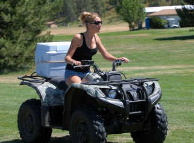 
In true North Idaho fashion, beer cart girl Melissa Dennis drives a camo ATV around Rimrock Golf Course in Chilco with cold drinks to sell to golfers. 
 (Jesse Tinsley / The Spokesman-Review)