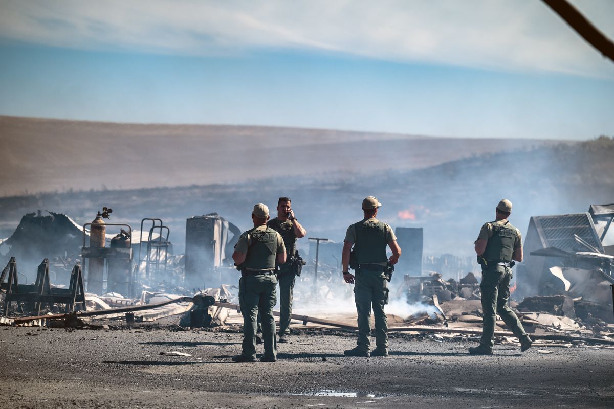Adams County Sheriff deputies examine the remains of a several structures destroyed by a fast-moving wildfire on the south side of the Adams County town of Lind. The Adams County Sheriff’s Office reported that six homes have been destroyed in the fast moving blaze that forced the evacuation of the town.  (COLIN MULVANY/THE SPOKESMAN-REVI)