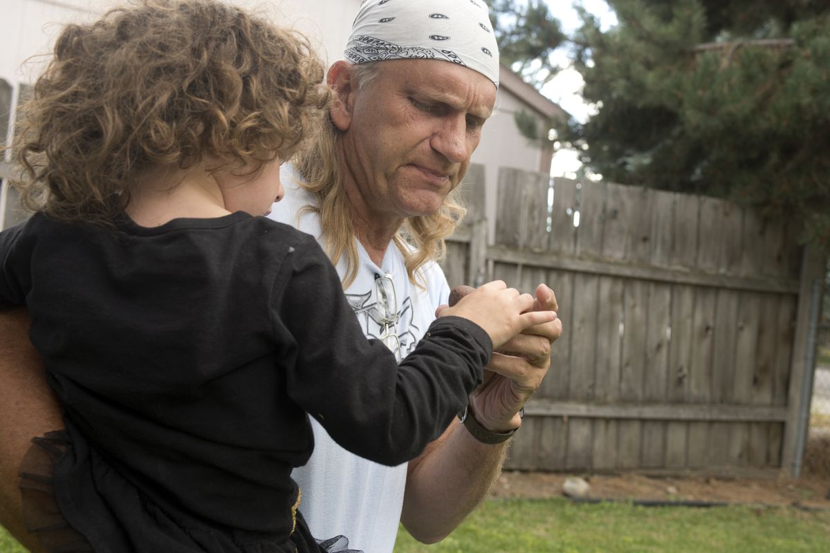 Bob Salsbury takes a rock handed to him by his granddaughter at his Spokane Valley home. He’s in the process of adopting her.