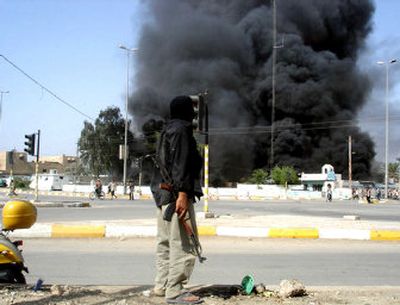 
A gunman stands on a street corner as a building burns in the southern Iraqi city of Amarah on Friday. Anti-American cleric Muqtada al-Sadr's militia briefly seized control of the city. 
 (Associated Press / The Spokesman-Review)