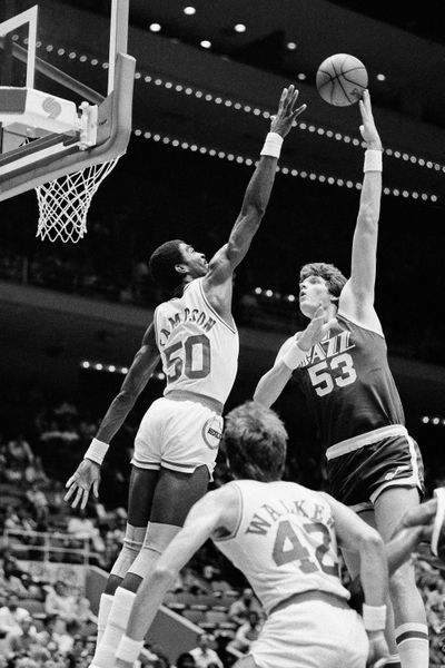 In this Nov. 11, 1983 photo, Utah Jazz center Mark Eaton, right, puts a shot up and over Houston Rockets center Ralph Sampson during an NBA basketball game in Houston. Eaton, the 7-foot-4 shot-blocking king who twice was the NBA's defensive player of the year during his career with the Utah Jazz, has died, the team said Saturday, May 29, 2021. He was 64.  (Associated Press)