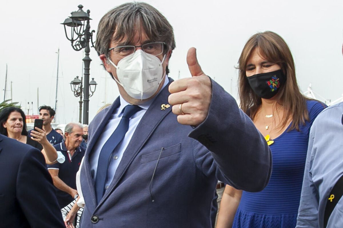 Catalan separatist leader Carles Puigdemont, left, gives thumbs up as he walks with the Speaker of the Catalan Parliament Laura Borras in Alghero, Sardinia, Italy, Saturday, Sept. 25, 2021. Puigdemont took a leisurely walk in the Sardinian city, waving to supporters, a day after a judge freed him from jail pending a hearing on his extradition to Spain, where the political firebrand is wanted for sedition.  (Francesca Salaris)