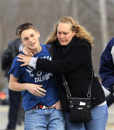 Doug Gasper, a ninth grader at Chardon High School, is hugged by his mother, Sandy, as they leave Maple Elementary School today in Chardon, Ohio. Students assembled at Maple Elementary School after a shooting took place at the high school. A gunman opened fire inside the high school's cafeteria at the start of the school day, wounding four students, officials said. A suspect is in custody. (AP/Tony Dejak)