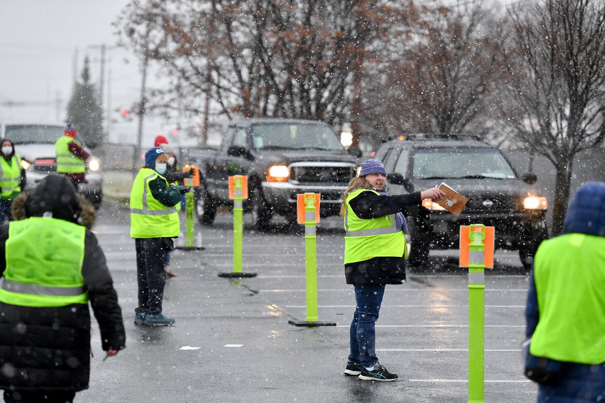 Volunteers sport green vests and brave a snow shower as they stage cars during Tom