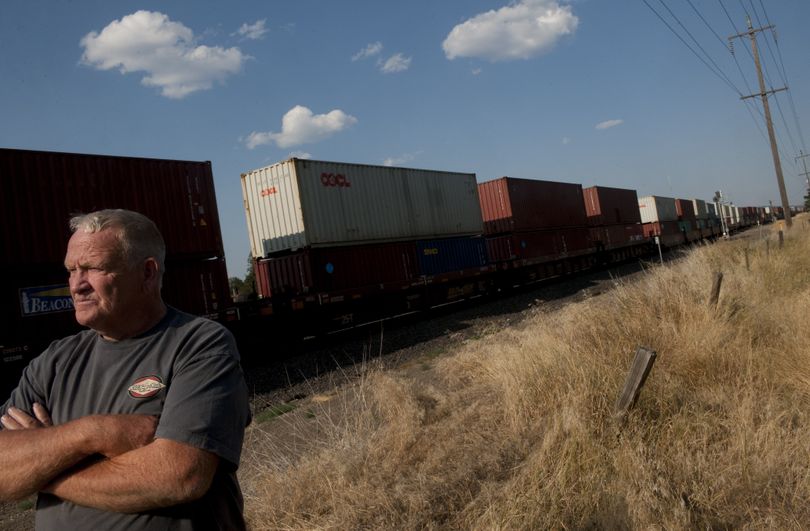 Spokane Valley resident Dennis Bonnett stands near his front yard as a freight train rolls through the Park Road crossing Aug. 4. Bonnett has lived near the crossing for 30 years and says he has watched BNSF build two more tracks through the crossing in that time. (Tyler Tjomsland)