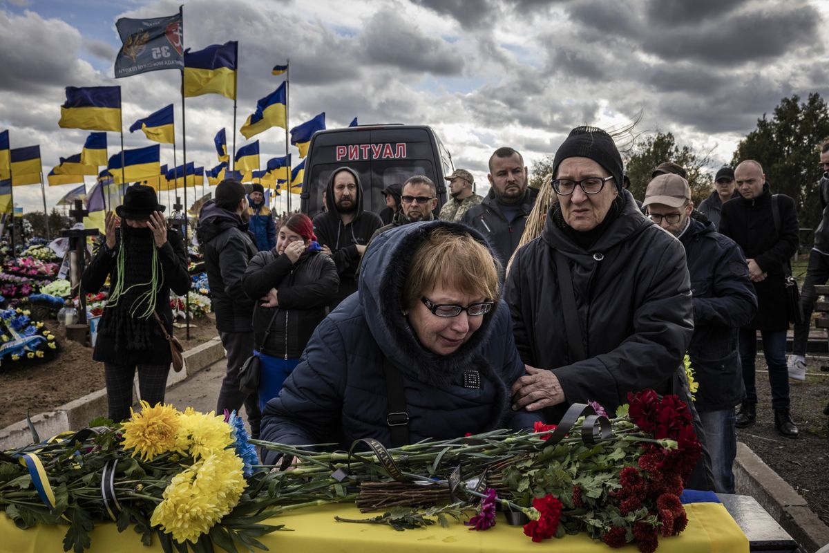 Women mourn a fallen Ukrainian soldier at a cemetery on the outskirts of Kherson last year.   (Ed Ram for The Washington Post)